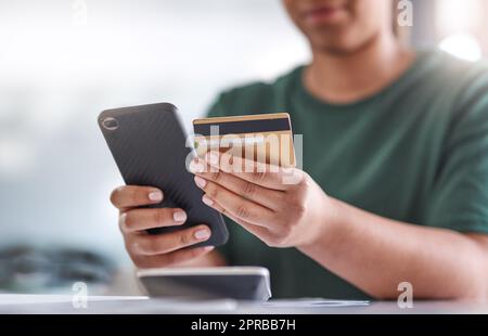 Payer des factures moins les files d'attente de la banque. Une femme méconnaissable utilisant un smartphone et une carte de crédit à son bureau. Banque D'Images