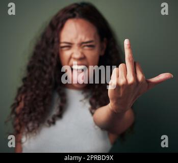 N'appuyez pas sur mes boutons. Photo studio d'une jeune femme montrant son doigt du milieu sur un fond vert. Banque D'Images