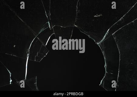 Vue en gros plan de verre brisé avec fissures sur fond noir Banque D'Images