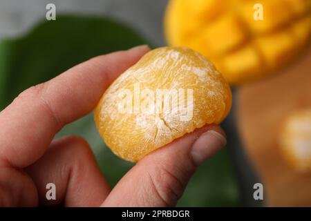 Femme tenant de délicieux mochi de mangue, gros plan. Cuisine japonaise Banque D'Images
