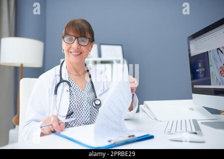 J'espère que cette paperasse est envoyée à temps. Une femme médecin remplit la paperasse à son bureau. Banque D'Images