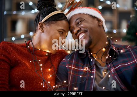 La magie de Noël est une sensation si merveilleuse. Un jeune couple célébrant Noël à la maison. Banque D'Images