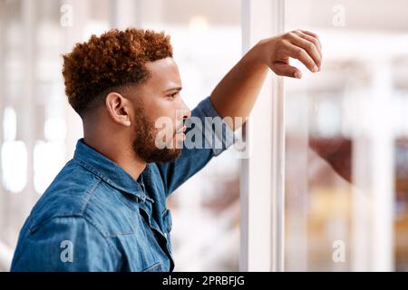 HES est prêt pour le prochain défi. Un jeune homme charmant et très attentionné, qui se tient debout devant une fenêtre dans son bureau. Banque D'Images