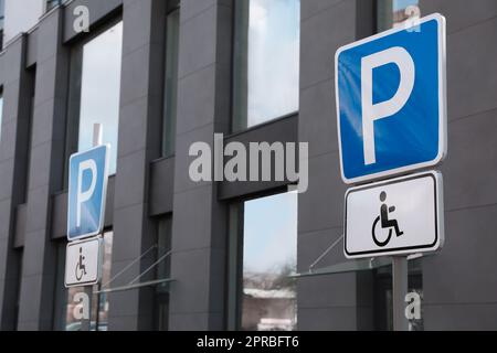 Panneau de signalisation parking pour personnes handicapées à proximité d'un bâtiment moderne Banque D'Images