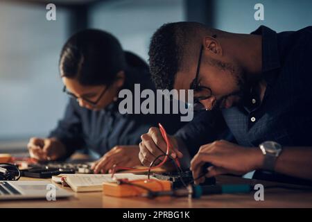 Faire réparer les choses avant la fin de l'aube. Deux jeunes techniciens réparent le matériel informatique ensemble. Banque D'Images