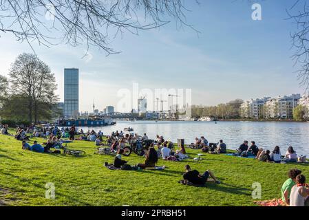 Les gens bronzent sur les rives de la rivière Spree au printemps à Treptower Park pendant une chaude journée de printemps à Berlin Treptow, Allemagne, Europe Banque D'Images