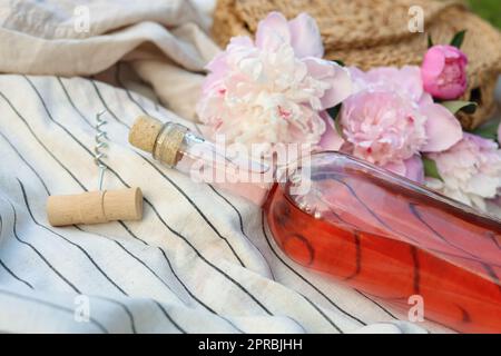 Bouteille de vin de rose et superbes pivoines sur une couverture légère, en gros plan Banque D'Images