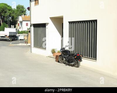 Belle moto noire garée près de la maison le jour ensoleillé Banque D'Images