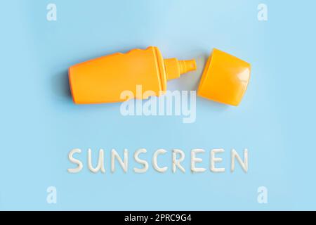 crème solaire, bouteille orange, protection solaire sur fond bleu, espace copie. vaporiser pour protéger contre les coups de soleil. Banque D'Images