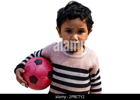 Petit garçon debout sur la cour avec un football de football. Jeune garçon actif Profitez d'une journée d'hiver ensoleillée à l'extérieur. Banque D'Images