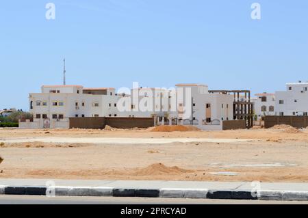 Maisons rectangulaires blanches arabes dans le désert avec des fenêtres sur fond de sable jaune et ciel bleu en Egypte et noir et blanc barré. Banque D'Images