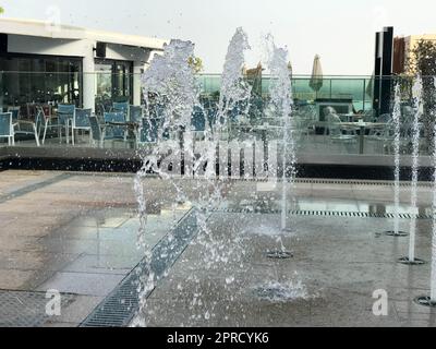 Une petite belle fontaine de chant en plein air, dans la rue. Gouttes d'eau, jets d'eau congelés dans l'air en vol sur fond d'un Banque D'Images