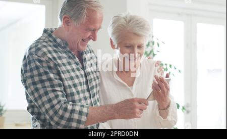 Écoutons ce que font les enfants. un heureux couple senior regardant quelque chose sur un téléphone portable. Banque D'Images