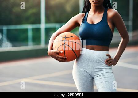 Je suis sur le terrain. Une sportswoman méconnaissable debout sur le terrain seul et tenant un basket-ball pendant la journée. Banque D'Images