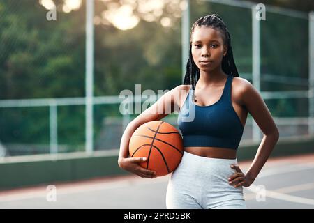 Je me sens comme à la maison sur le terrain. Une jeune sportswoman attrayante debout sur le terrain seul et tenant un basket-ball pendant la journée. Banque D'Images