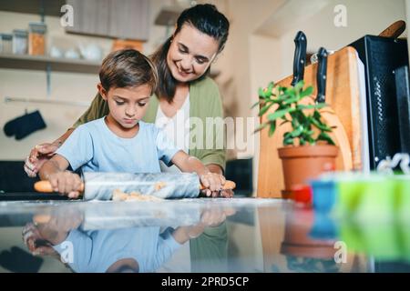 Laissez le temps de la famille se dérouler. Un adorable petit garçon qui cuit avec sa mère à la maison. Banque D'Images