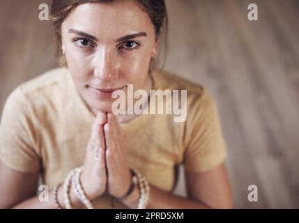 Je suis en paix avec moi-même. Portrait court d'une jeune femme attrayante assise à l'intérieur et utilisant des perles de mala pendant sa routine de méditation. Banque D'Images