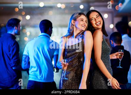 Nous sommes sur le feu. Deux jeunes femmes gaies prenant des boissons tout en dansant sur la piste de danse d'une discothèque le soir. Banque D'Images