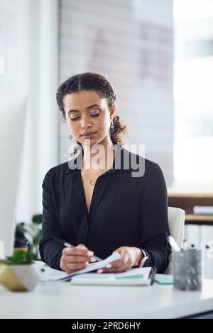 Tous les plans doivent d'abord être approuvés. Une jeune femme d'affaires passe par la paperasse dans un bureau. Banque D'Images