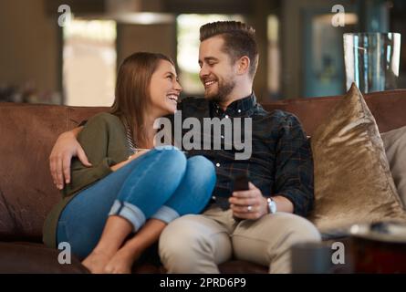 Je suis si heureux que vous le miez. Un jeune couple qui se détend sur le canapé à la maison. Banque D'Images