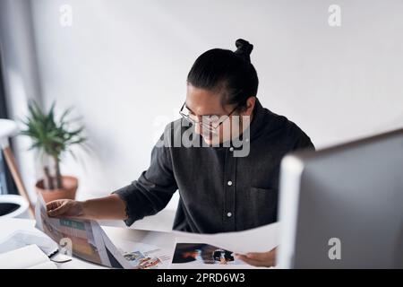 Un beau jeune homme d'affaires qui regarde la paperasse et qui s'assoit seul à son bureau. Banque D'Images