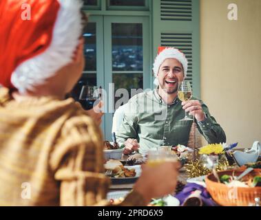 HES se sent très joyeux aujourd'hui. Portrait d'un beau jeune homme s'appréciant lors d'une fête de Noël avec ses amis et sa famille. Banque D'Images