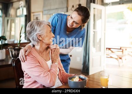 Appréciez-vous votre petit-déjeuner. Une jeune infirmière s'occupe d'une femme âgée pendant le petit-déjeuner dans une maison de soins infirmiers. Banque D'Images