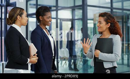 Les femmes qui réussissent ont beaucoup de choses en commun. Trois jeunes femmes d'affaires ont une discussion au travail. Banque D'Images