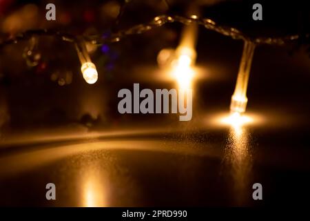 Des lumières de Noël colorées comme une chaîne de lumières multicolores pour une bonne année et Saint-Sylvestre comme décoration de fête et ornement pour l'arbre de Noël à l'heure de l'avènement brillant dans la nuit sainte sombre Banque D'Images