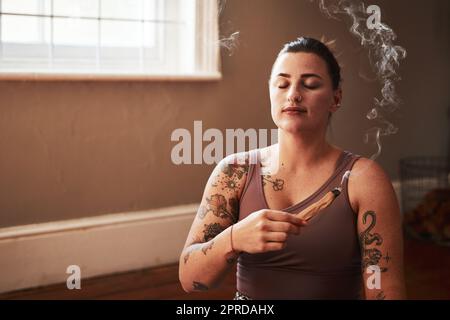 La méditation me porte plus calmement à travers ma journée. Une jeune femme brûlant un bâton de palo santo à la maison. Banque D'Images