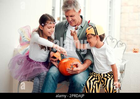 Nous avons fait des bons moments avec notre grand-père. Deux adorables jeunes frères et sœurs ont fait des citrouilles pour Halloween avec leur grand-père à la maison. Banque D'Images