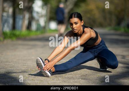 Se préparer à faire sortir son cœur. Portrait d'une jeune femme sportive qui étire les jambes tout en faisant de l'exercice à l'extérieur. Banque D'Images