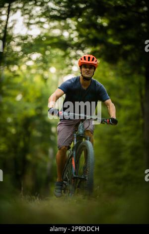 Jeune homme avec son vélo tout-terrain allant pour une promenade au-delà des limites de la ville dans une belle forêt, obtenant la dose quotidienne de cardio Banque D'Images