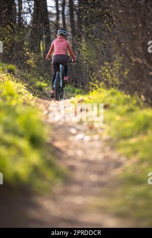 Jolie, jeune femme avec son vélo tout-terrain allant pour un tour au-delà des limites de la ville, obtenant la dose quotidienne de cardio Banque D'Images