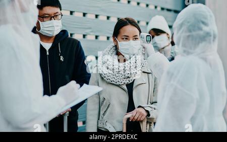 Une femme en voyage obtient une analyse de la température des Covid à la frontière avec la sécurité médicale effectuant un test de dépistage de la sécurité pendant une pandémie. Personnes étrangères ou voyageur arrivant à un aéroport avec masque facial Banque D'Images