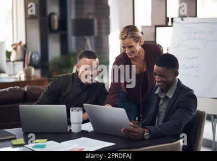 Dépasser régulièrement les attentes. Groupe d'hommes et de femmes d'affaires travaillant ensemble sur un ordinateur portable dans un bureau. Banque D'Images