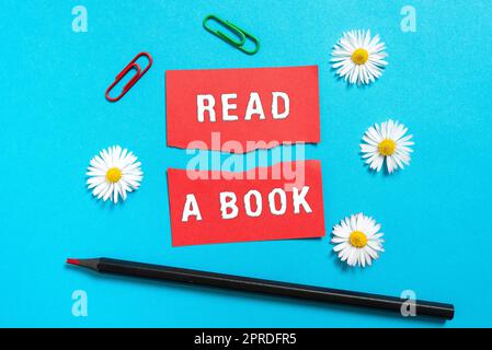 Panneau de texte indiquant Lire Un livre. Vitrine d'affaires Profitez de la littérature activité traditionnelle Apprenez de nouvelles choses déchirées Note avec de nouvelles idées avec crayon, fleurs et trombones autour. Banque D'Images