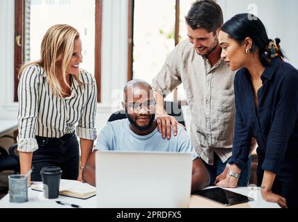 Bon travail. Un groupe de collègues se sont rassemblés autour d'un ordinateur portable au bureau. Banque D'Images