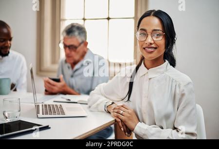 La réussite se conjuque lorsque nous nous réunissons. Portrait d'une jeune femme d'affaires ayant une réunion avec des collègues dans un bureau moderne. Banque D'Images