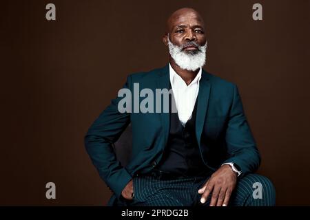 Le seul conseil que j'ai pour vous est de travailler dur. Photo studio d'un homme d'affaires mûr se posant sur un fond marron. Banque D'Images