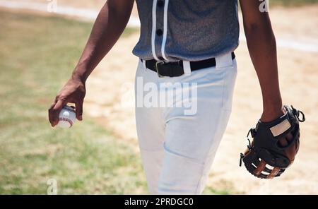 Celui qui tient le ballon est le patron. Un homme debout sur un terrain et tenant un gant de baseball et un ballon à un match. Banque D'Images