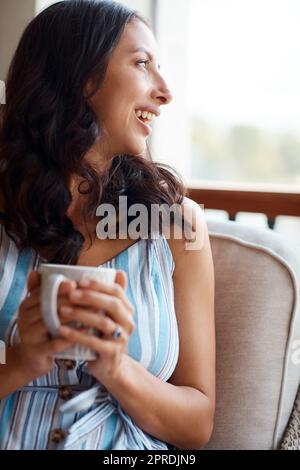 Bonjour à une autre belle journée. une jeune femme buvant du café tout en se relaxant sur le porche à la maison. Banque D'Images