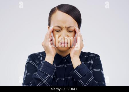 Mon cerveau ne peut plus le prendre : une jeune femme qui tient la tête tout en souffrant d'un mal de tête sur fond gris. Banque D'Images