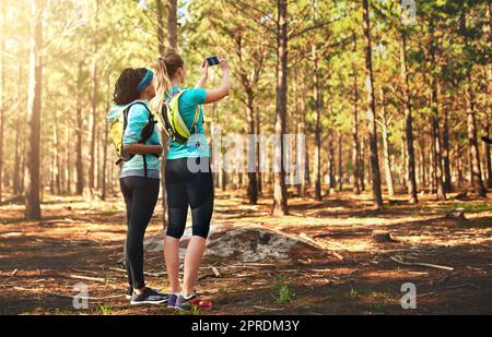 Ne prenez rien d'autre que des souvenirs avec vous. Deux jeunes femmes sportives prenant des photos tout en étant dans la nature. Banque D'Images