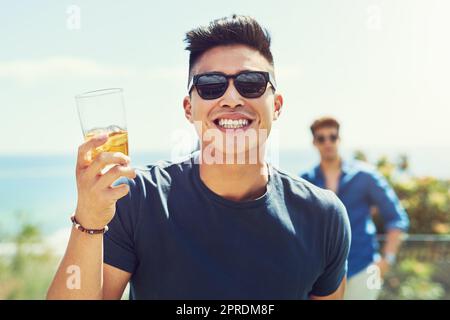 Mon visage dit tout, je suis plus que heureux. Portrait d'un beau jeune homme levant son verre pour un toast tout en se relaxant dehors avec ses amis. Banque D'Images