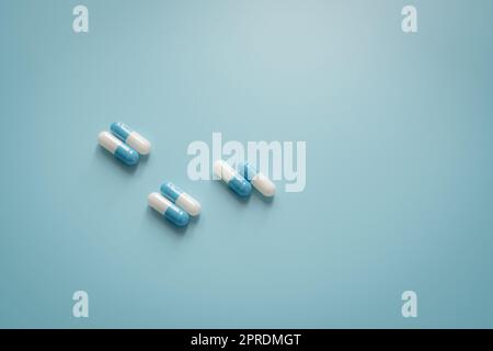 Paires de pilules de capsule d'antibiotique blanc-bleu sur fond bleu. Médicament antibiotique. Médicament sur ordonnance. Concept de pharmacologie et de dose recommandée. Industrie pharmaceutique. Concept médical et de soins de santé. Banque D'Images