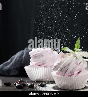 Marshmallows aux fruits martionnés dans une tasse en papier sur un plateau en bois noir, délicieux dessert Banque D'Images