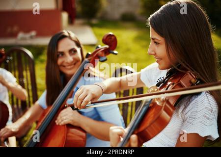 J'ai appris mon amour pour la musique de ma mère. Une belle mère jouant des instruments avec son adorable fille dehors. Banque D'Images