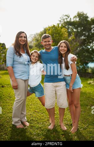 C'est une famille de livres d'images. Portrait d'une jeune famille de quatre personnes debout à l'extérieur. Banque D'Images