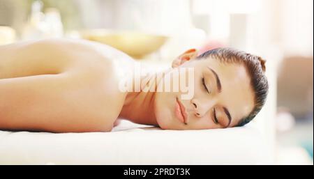 Aujourd'hui est réservée à vous. Une jeune femme se relaxant sur un lit de massage dans un spa. Banque D'Images